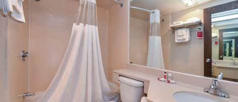 A bathroom with a shower, toilet, sink, and mirror.