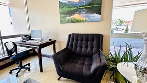 A modern office space with a desk, office chair, and a large landscape painting on the wall. - Ramada by Wyndham Grand Junction (Grand Junction)