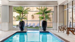 A swimming pool with two large vases of plants, a view of a lawn, and a seating area with chairs. - Sheraton Suites Galleria-Atlanta (Atlanta)