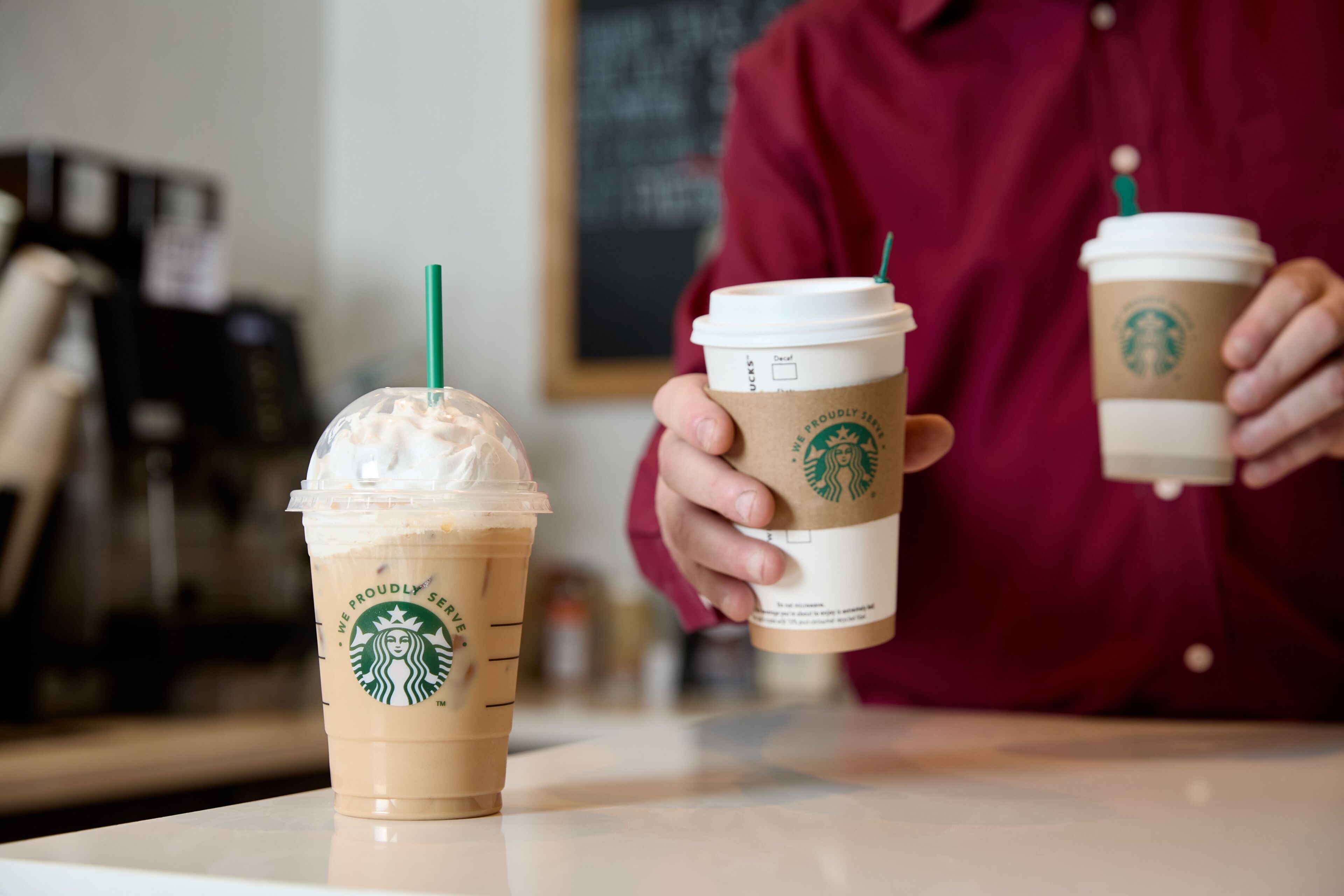 Two Starbucks cups, one with whipped cream and one without, on a table.