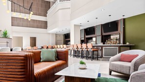 A modern hotel lobby with leather seating, a bar area, and a flat-screen TV. - Sheraton Suites Galleria-Atlanta (Atlanta)