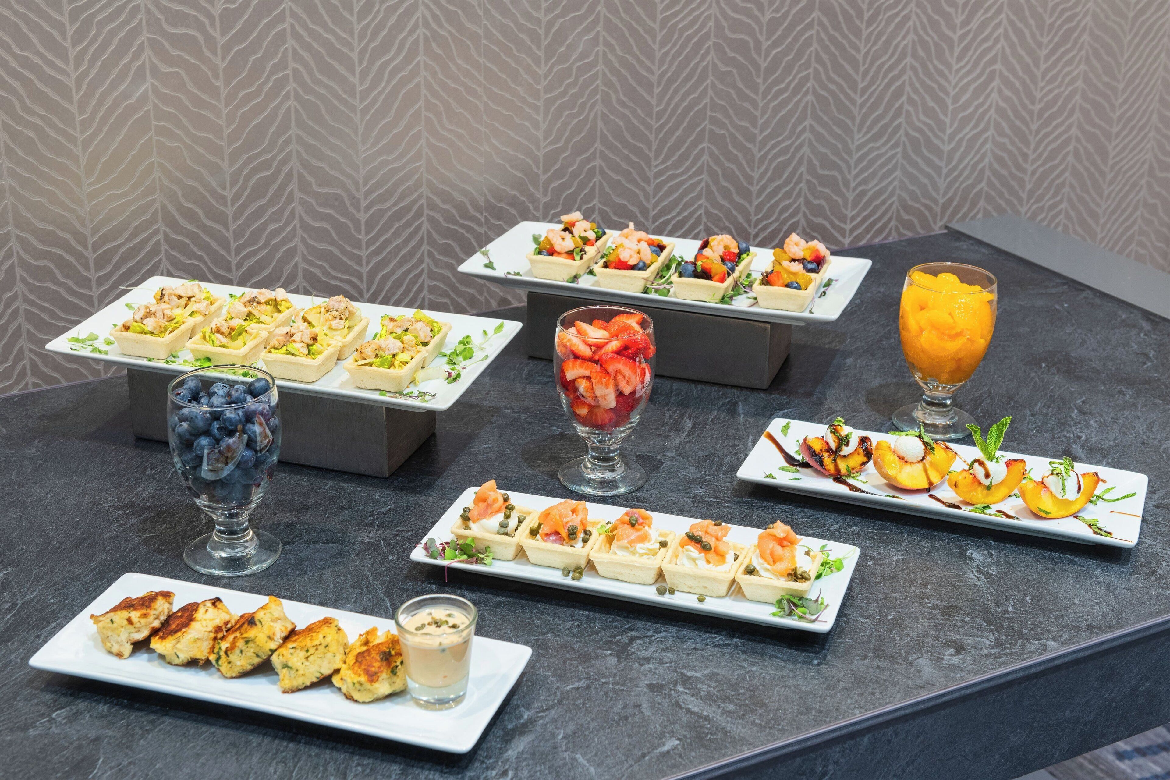 Variedad de aperitivos y postres sobre una mesa con un fondo de papel tapiz estampado.