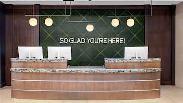 Un comptoir d’accueil doté de trois écrans d’ordinateur, un mur vert orné d’un message et un éclairage suspendu.