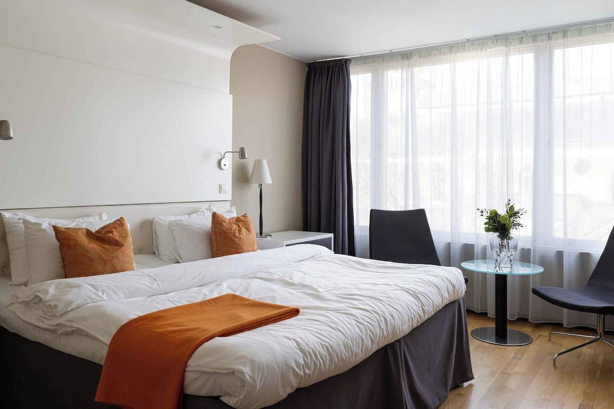 Ein modernes Hotelzimmer mit einem großen Bett, einem kleinen Tisch und einem Stuhl.