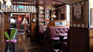 A cozy library with bookshelves, a clock, and comfortable seating areas. - Elite Stadshotellet Västerås (Vasteras)