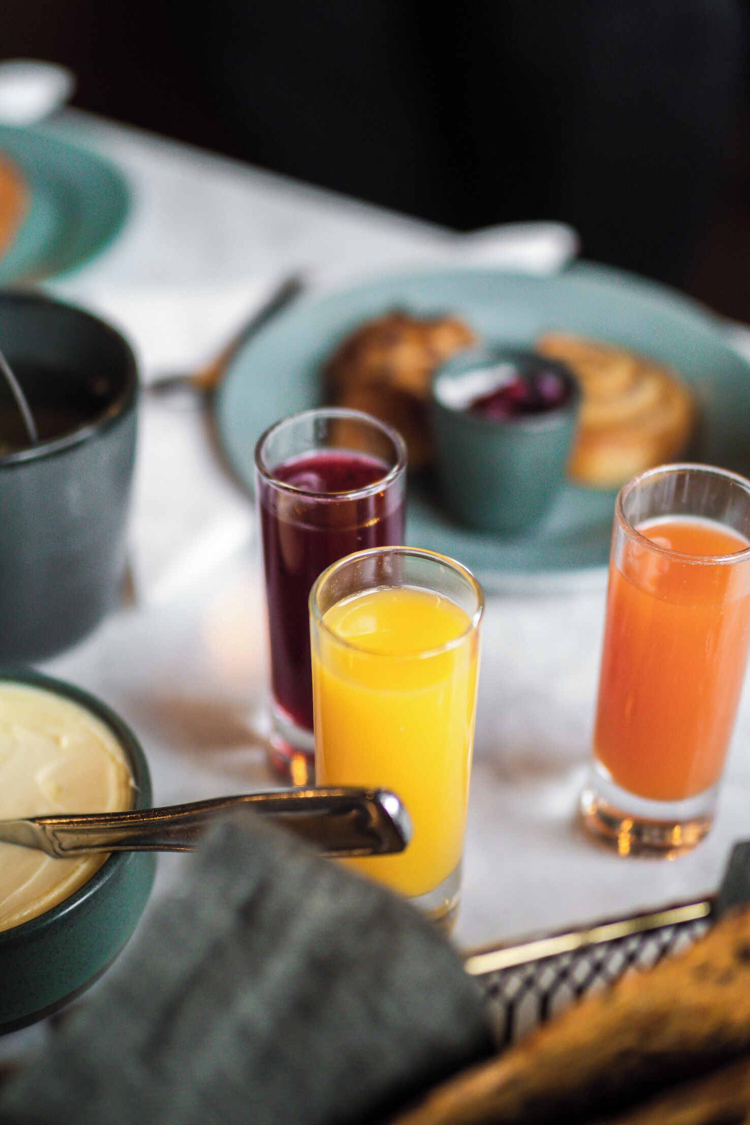 A breakfast setting with a variety of drinks and pastries on a table.