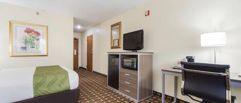 A hotel room with a bed, a desk with a computer, a television, and a cabinet.
