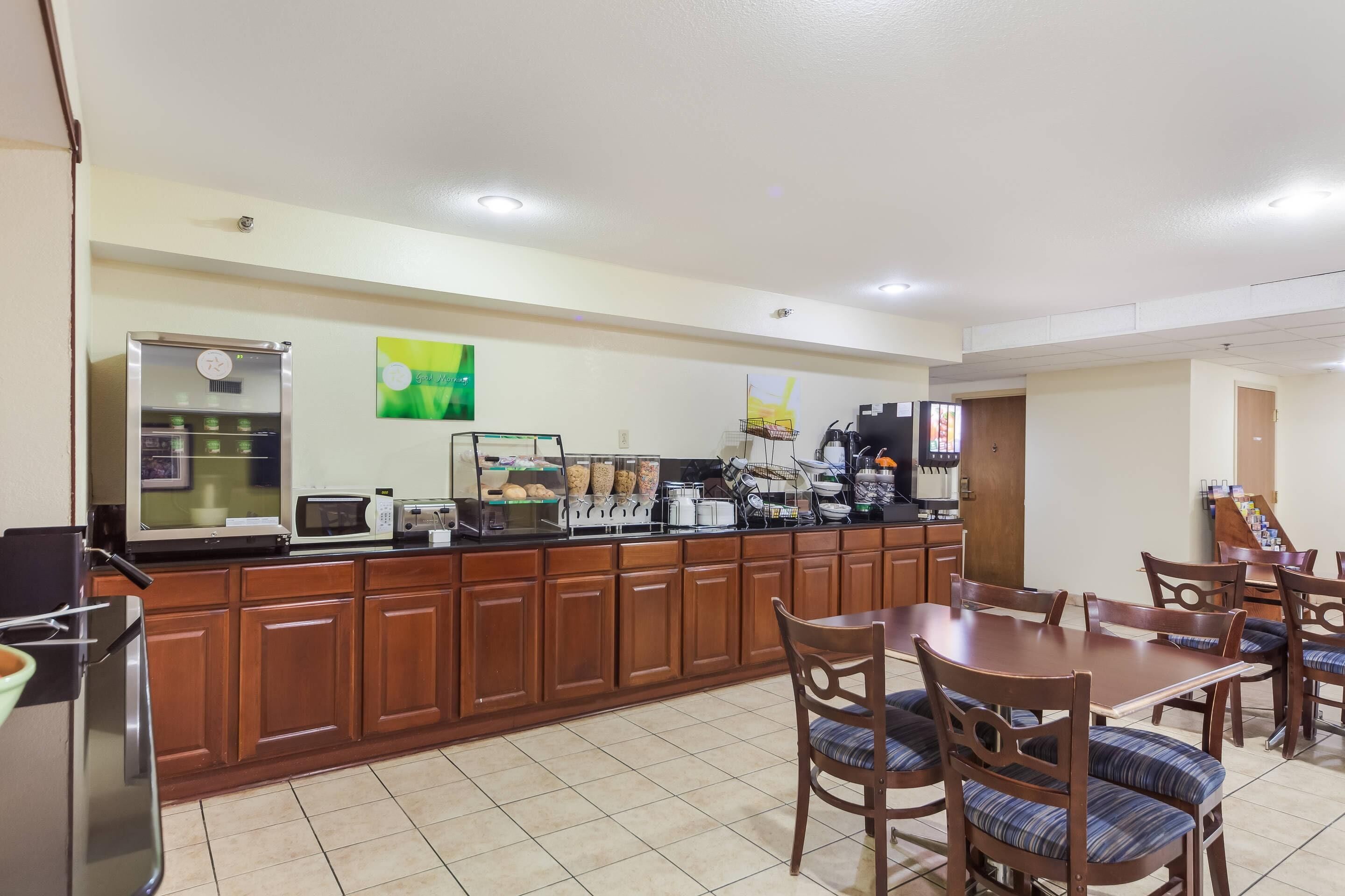 A hotel kitchen with wooden cabinets, a microwave, a coffee machine, and a buffet area.