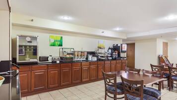A hotel kitchen with wooden cabinets, a microwave, a coffee machine, and a buffet area.
