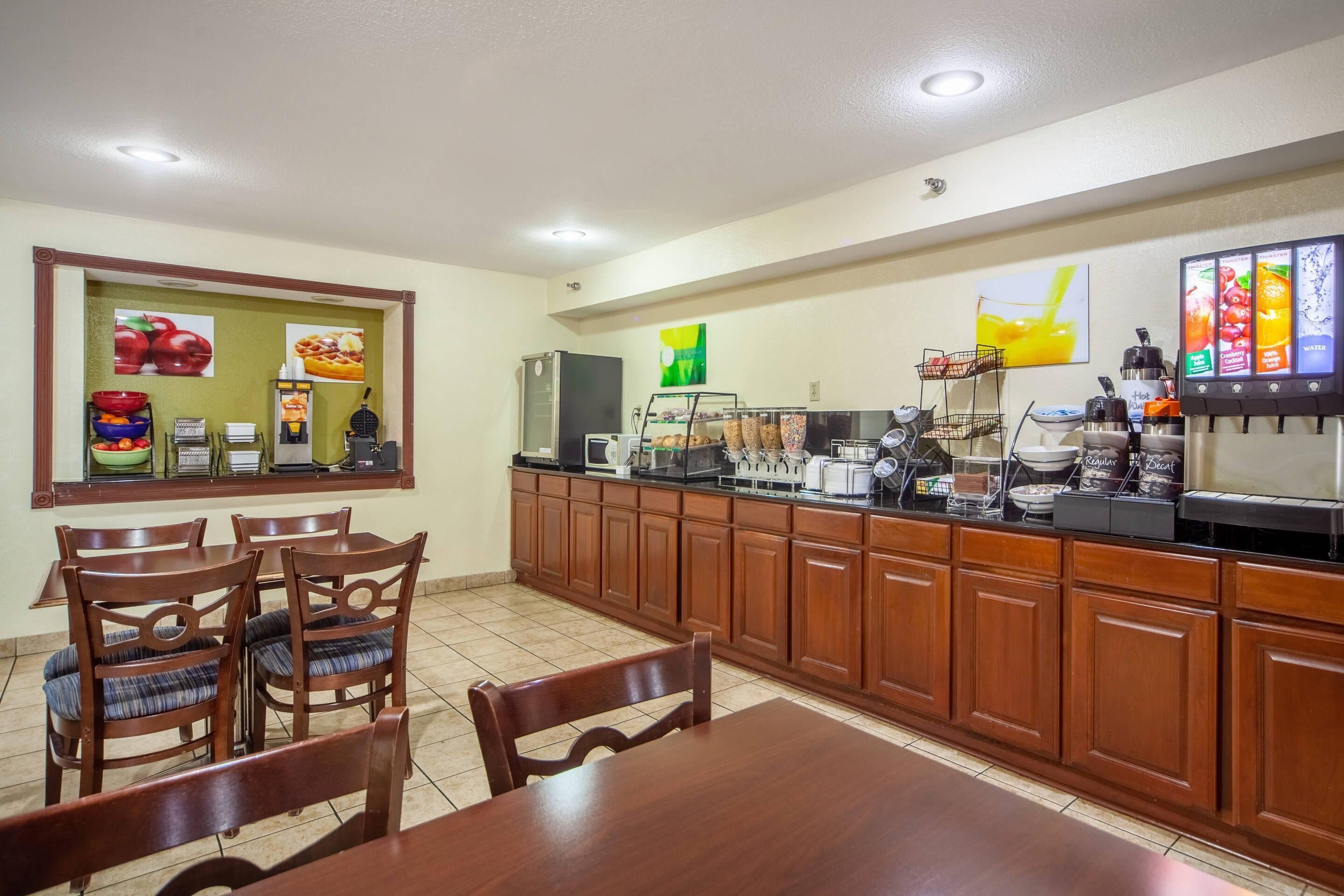 A hotel kitchen with wooden cabinets, a buffet area with food items, and a coffee station.