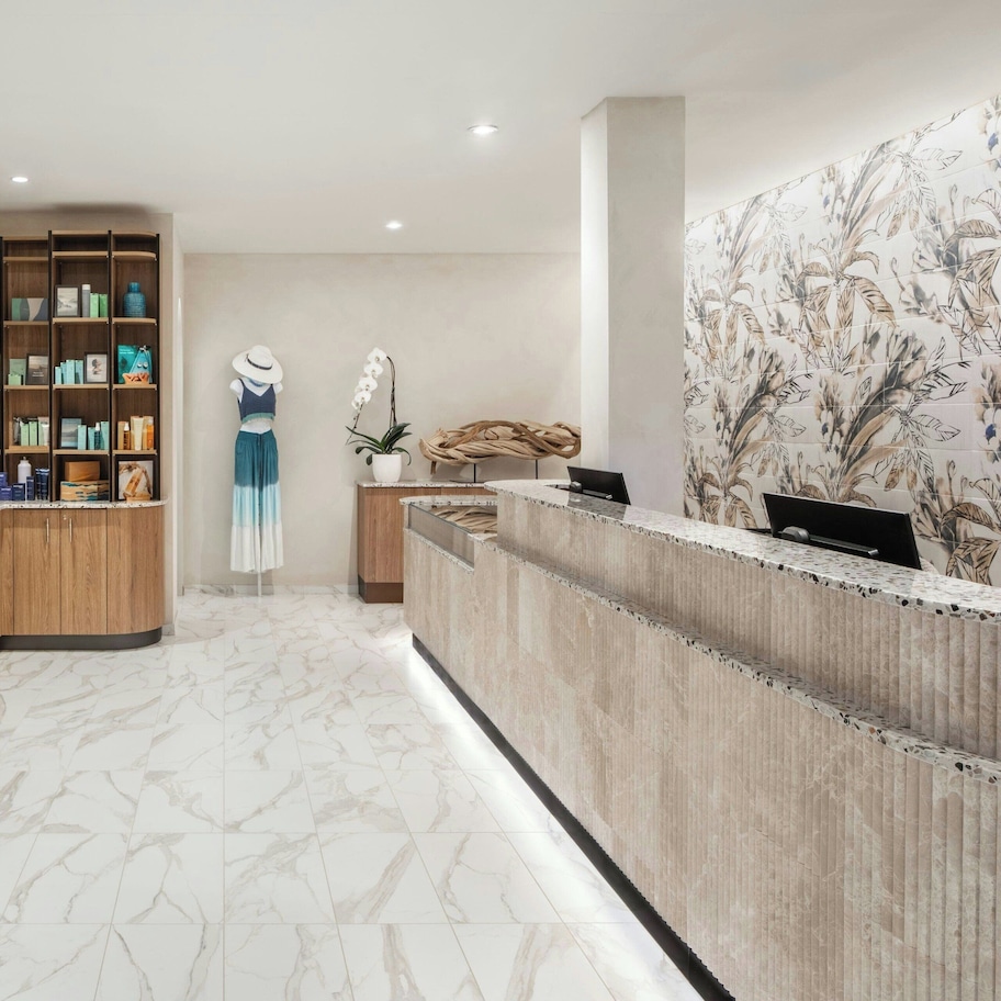 A reception area with a wooden reception desk, a large floral-patterned wall, and a marble-tiled floor.