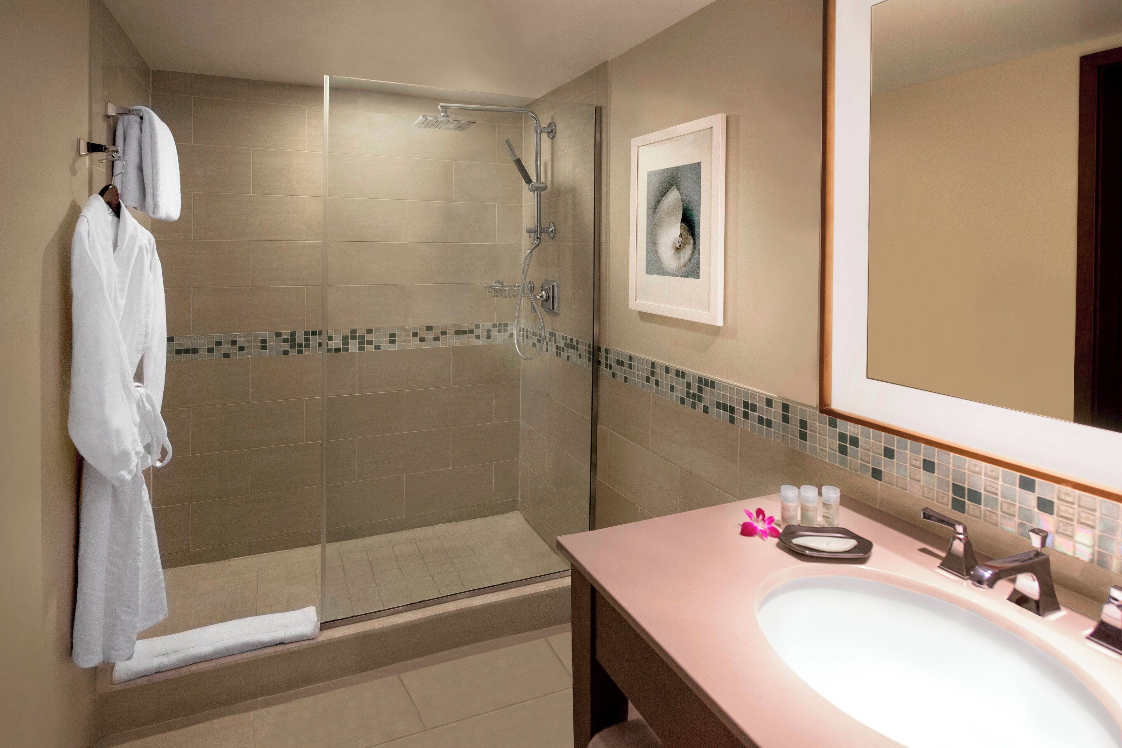 A bathroom with a glass-enclosed shower, a sink with a mirror, and a towel rack.