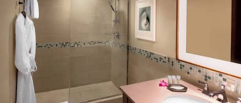 A bathroom with a glass-enclosed shower, a sink with a mirror, and a towel rack.