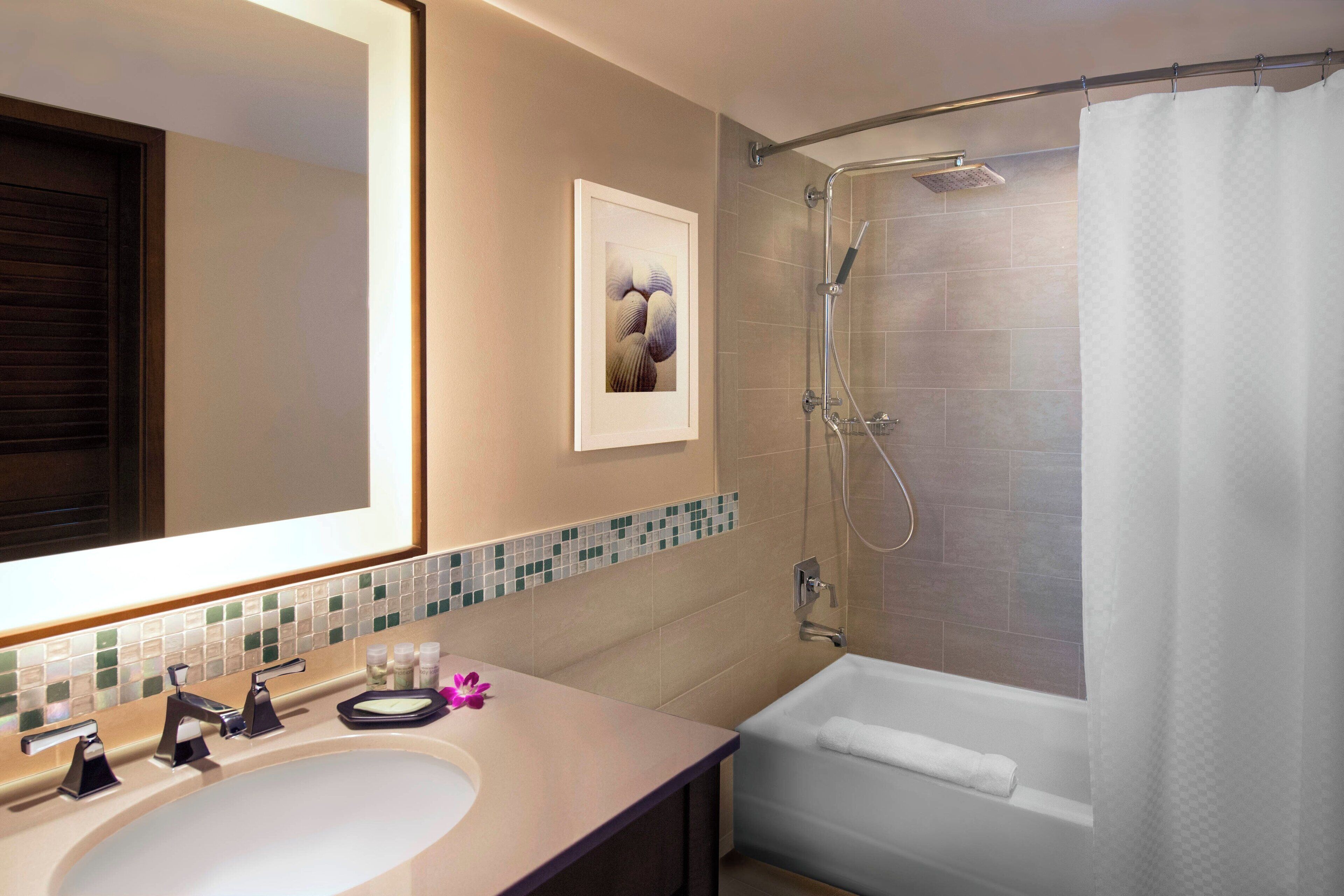 Une salle de bain avec un lavabo, un miroir, une douche et un tableau encadré au mur.