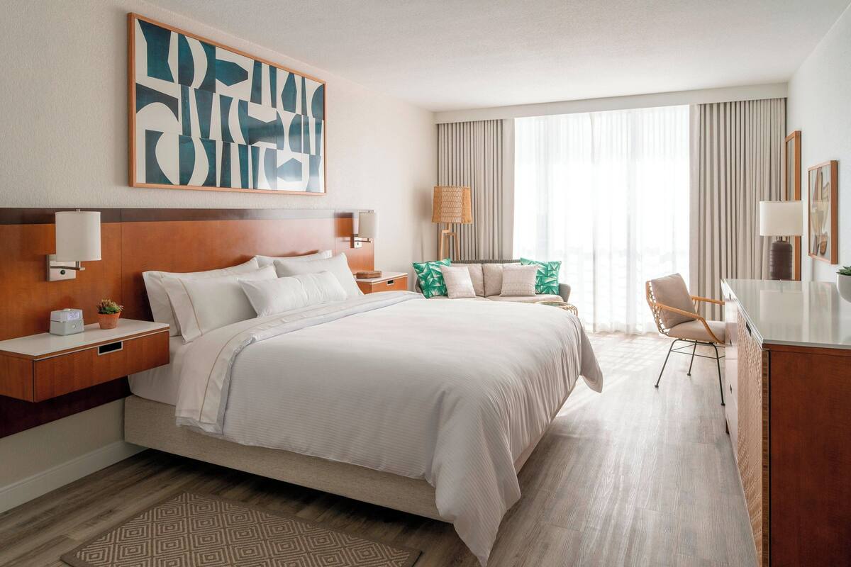 Une chambre d’hôtel avec un grand lit, des tables de chevet, un bureau et une chaise.
