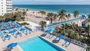 A hotel with a pool, beach view, and palm trees.