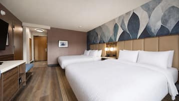 Una habitación de hotel con una cama grande, mesitas de noche, un escritorio y un cuadro en la pared.