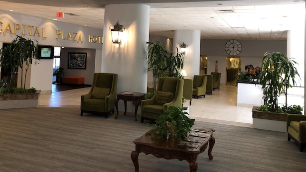 A lobby with green armchairs, a reception desk, and a large clock on the wall.