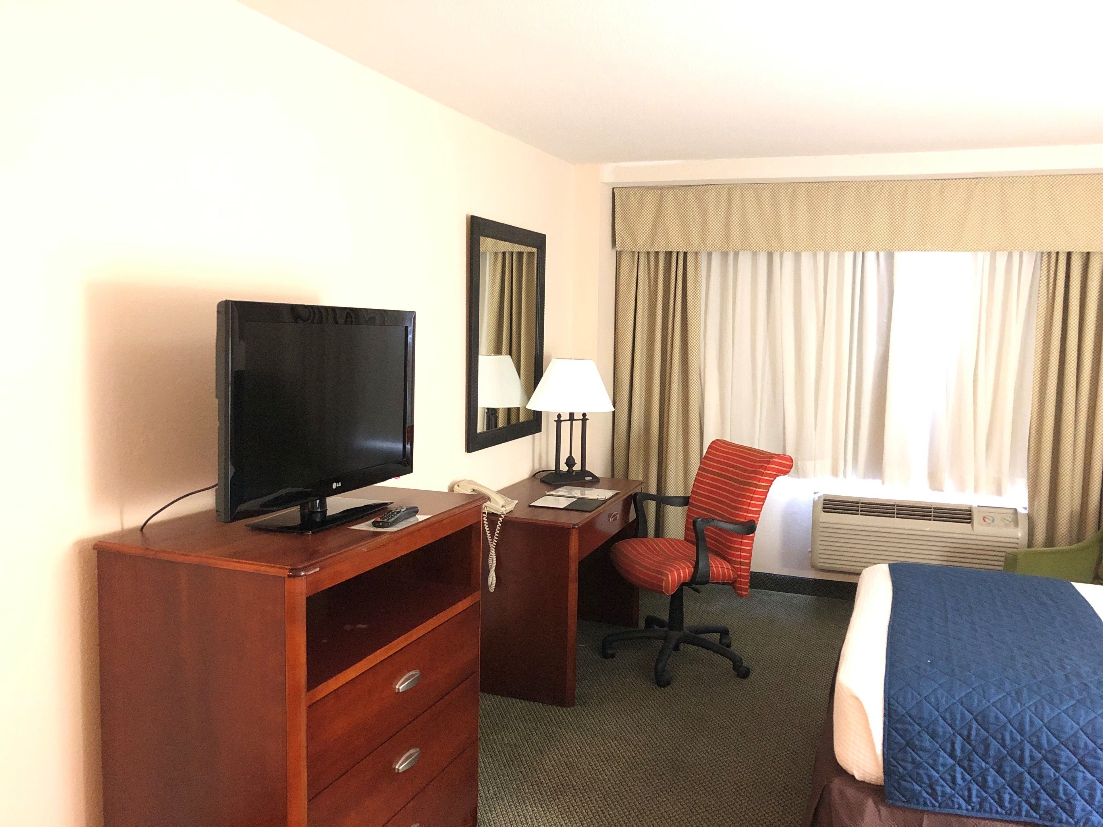 Una habitación de hotel con televisión, escritorio, silla y cama.