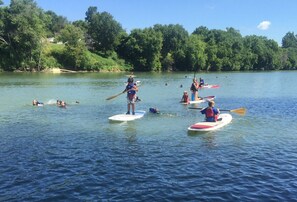 A group of people on paddleboards in a calm lake surrounded by trees. - Capital Plaza Hotel (Frankfort)