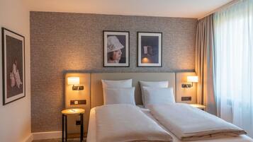Ein Hotelzimmer mit einem großen Bett, zwei Nachttischen, Wandleuchten und gerahmten Bildern an der Wand.