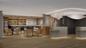 A modern bar area with wooden flooring, a bar counter, and a seating area with chairs and tables. - Mercure Parkhotel Mönchengladbach (Moenchengladbach)