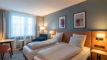 A hotel room with two beds, a desk, a chair, and two wall-mounted lamps.