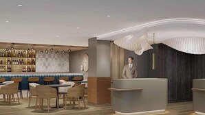 A modern bar area with a counter, seating, and a display of bottles. - Mercure Parkhotel Mönchengladbach (Moenchengladbach)