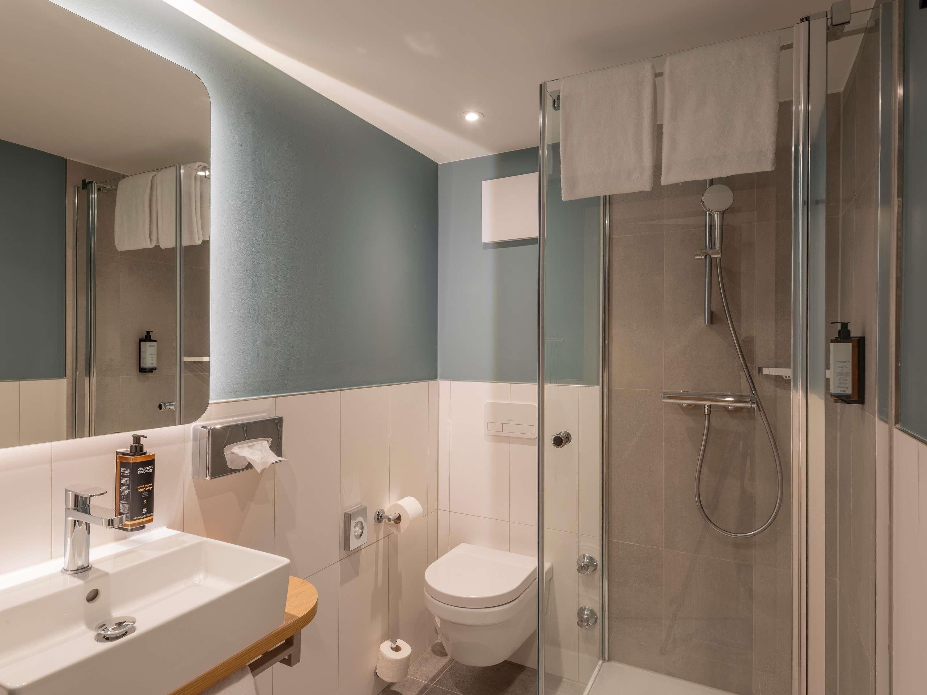 A modern bathroom with a glass-enclosed shower, a white sink, and a toilet.
