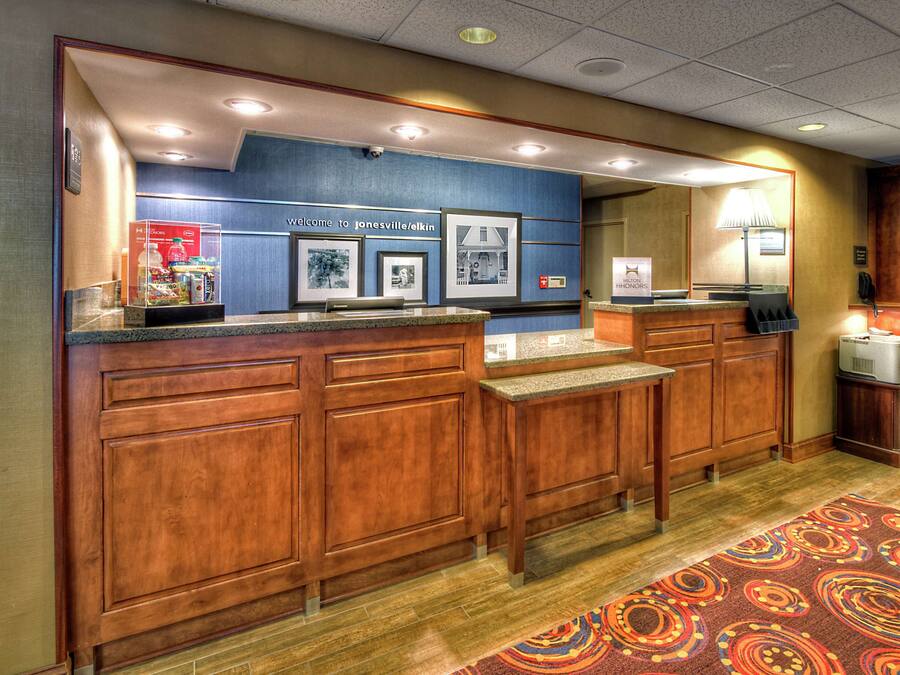A reception area with a counter, wooden cabinets, framed pictures, and a welcome sign.