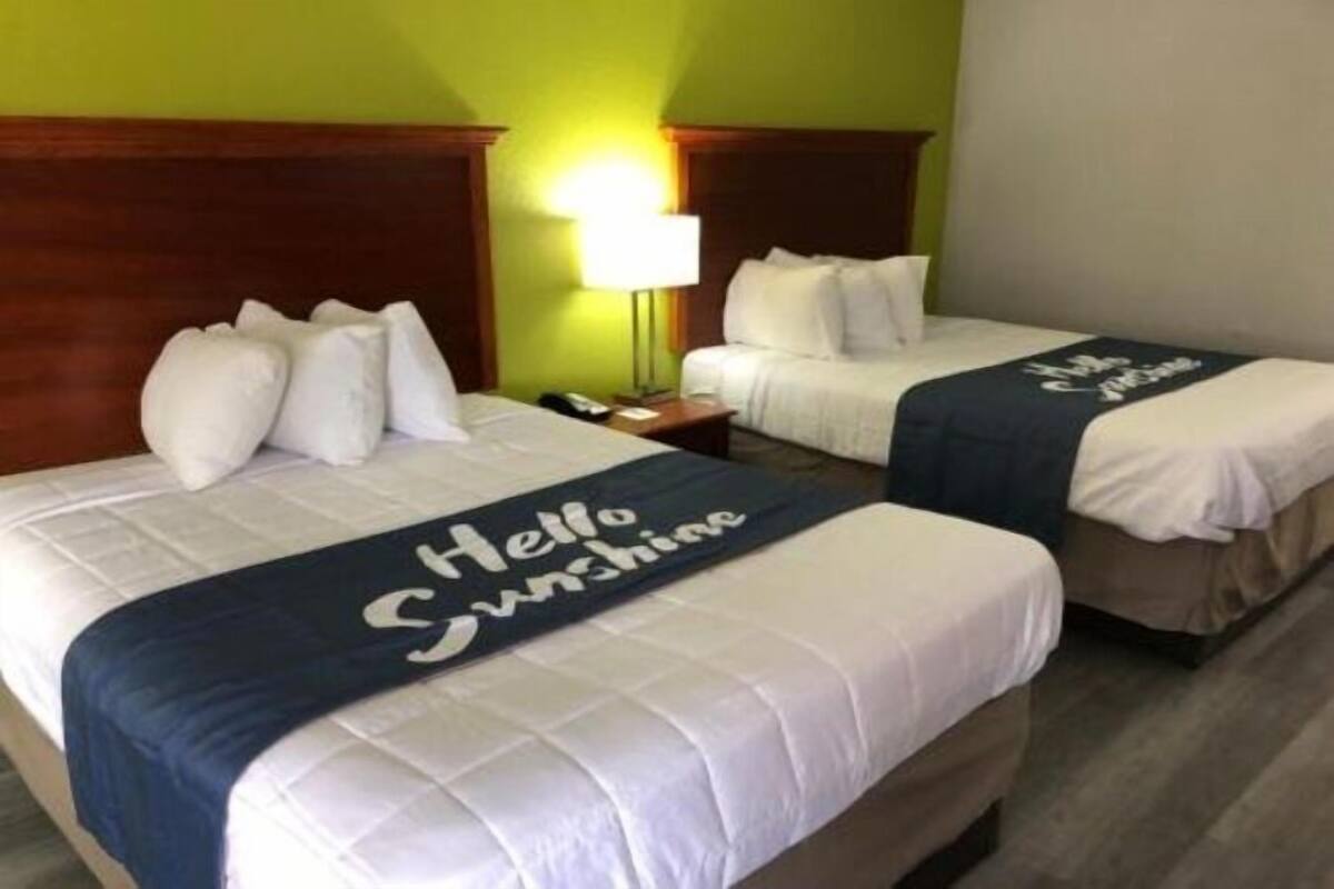 Ett hotellrum med två sängar, och varje säng har ett sängöverkast med texten ”Hej, solsken!”.