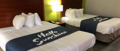 A hotel room with two beds, each with a 'Hello Sunshine' bedspread.