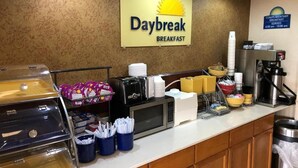 A breakfast counter with a sign reading "Daybreak Breakfast," a coffee machine, and various food items. - Days Inn by Wyndham Shorter (Shorter)
