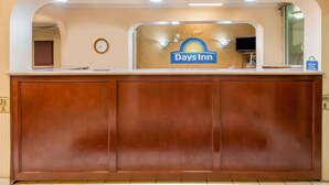 A reception desk with a 'Welcome! Days Inn' sign, a clock, and a television. - Days Inn by Wyndham Shorter (Shorter)