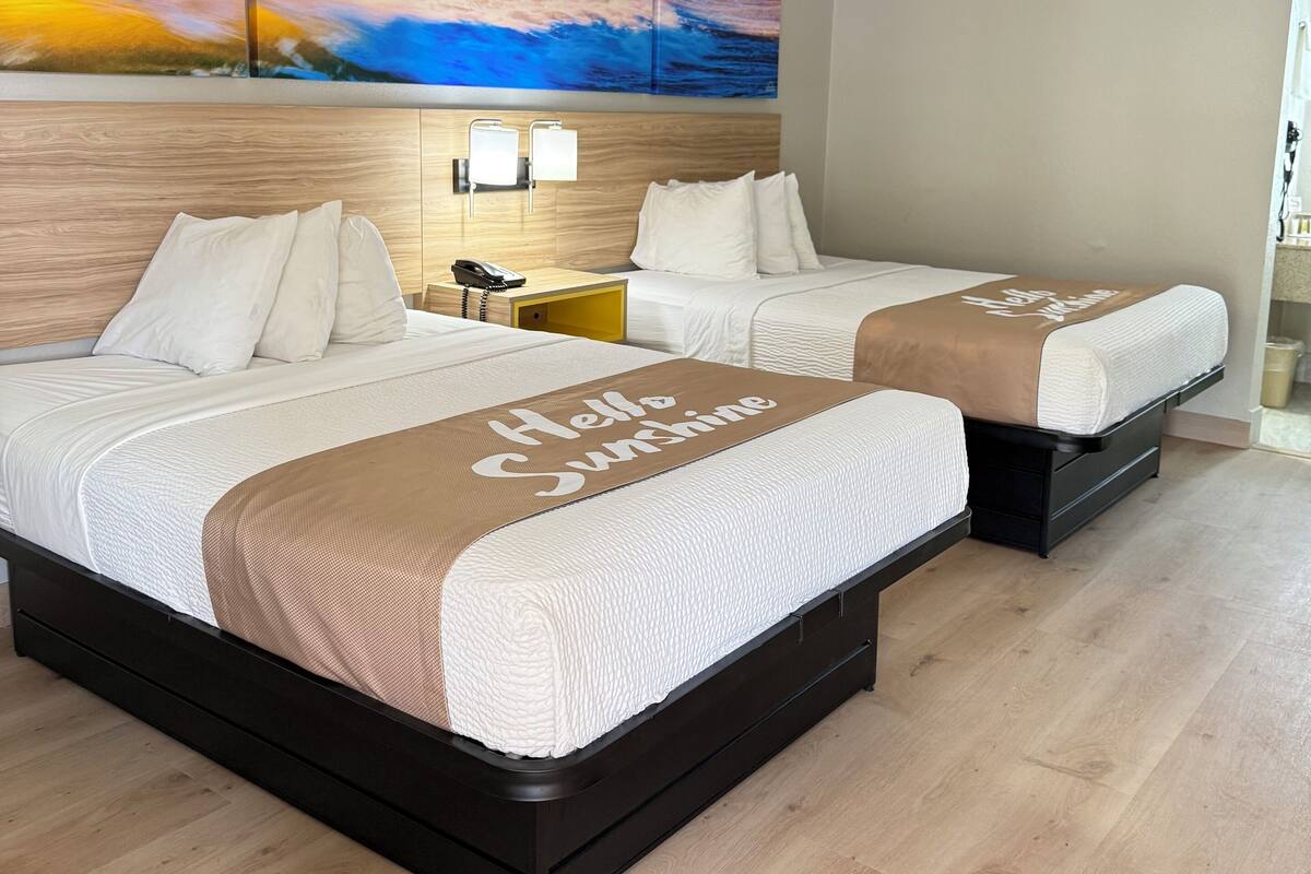 Ett hotellrum med två sängar, en stor, abstrakt målning på väggen och utsikt över havet.