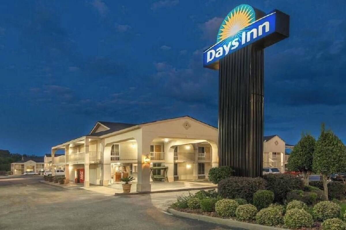 Ett Days Inn-hotell med en tydlig skylt, en parkeringsplats och en väl upplyst fasad.