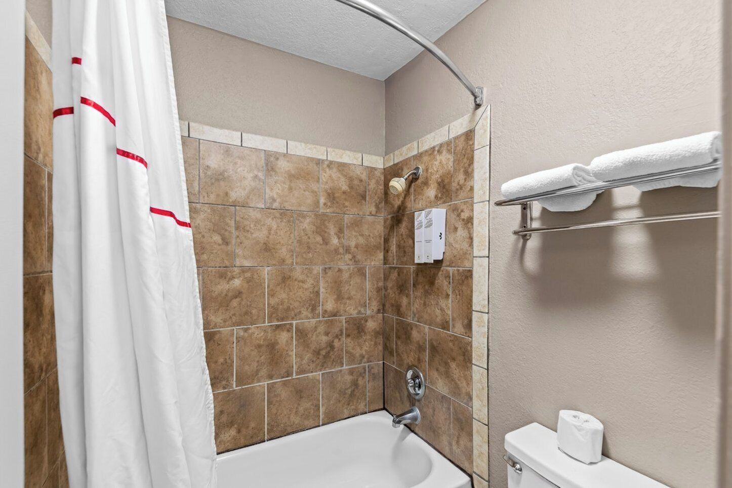 A bathroom with a shower, a bathtub, a toilet, and a towel rack.