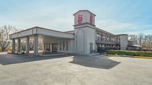A hotel with a covered outdoor area, a central tower with signage, and a parking lot. - Red Roof Inn Ardmore (Ardmore)