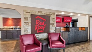 A Red Roof Inn reception area with a stone wall, a signboard, a reception desk, and two red leather chairs. - Red Roof Inn Ardmore (Ardmore)