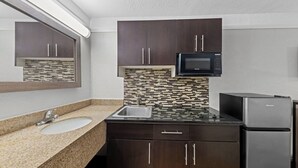 A compact kitchen with a granite countertop, a stainless steel sink, a microwave, and a refrigerator. - Red Roof Inn Ardmore (Ardmore)