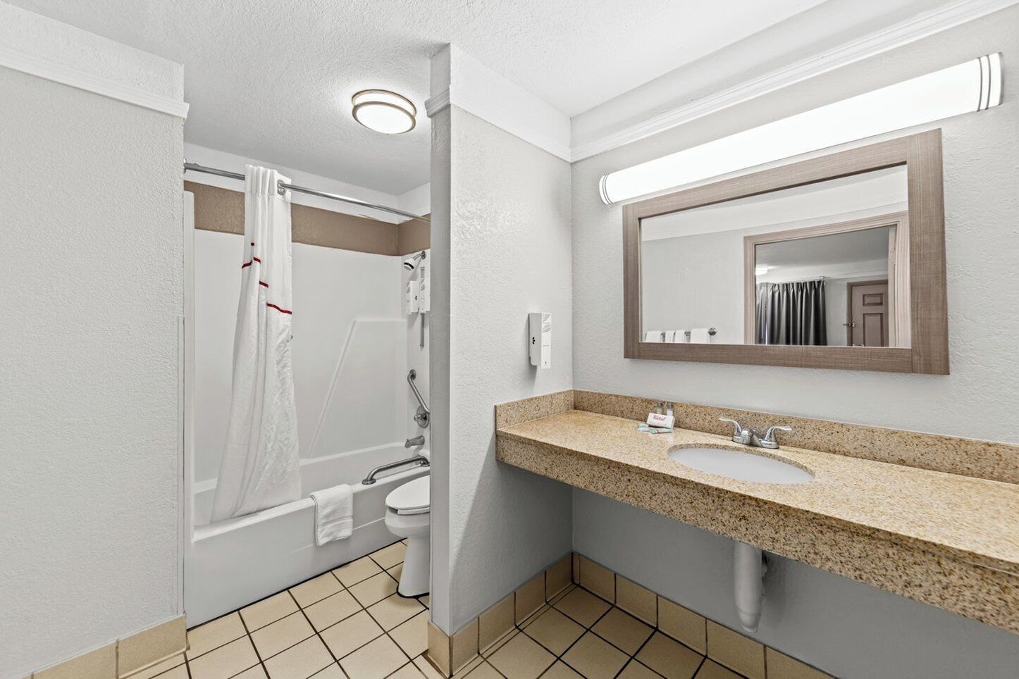 Un baño con lavamanos, espejo y ducha.