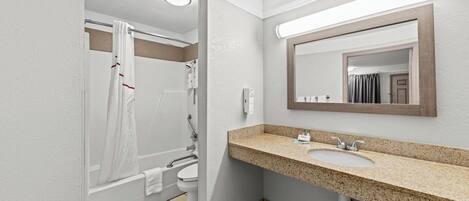 A bathroom with a sink, mirror, and shower.