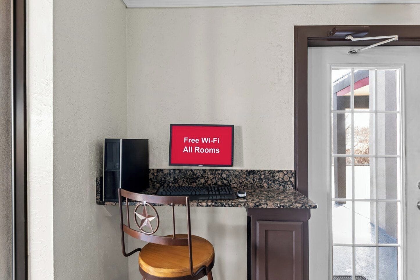 Una cocina con encimera, una silla, un cartel que dice 'Wi-Fi gratis en todas las habitaciones' y una puerta con ventanal.