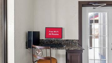 Una cocina con encimera, una silla, un cartel que dice 'Wi-Fi gratis en todas las habitaciones' y una puerta con ventanal.