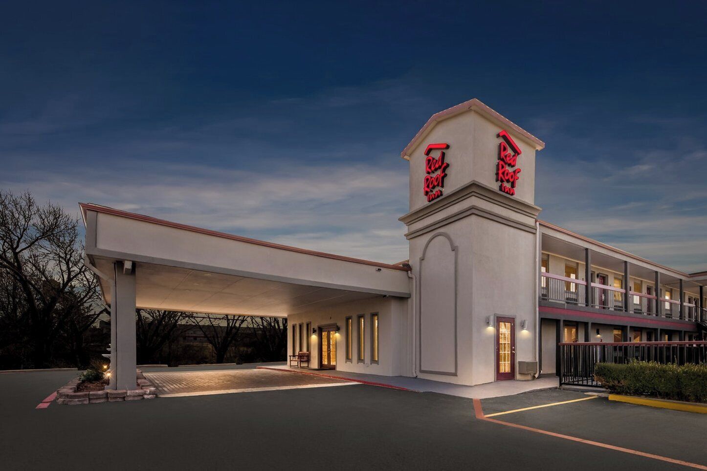 A motel with a central tower displaying the Red Roof Inn logo, a covered parking area, and a multi-story building with balconies.