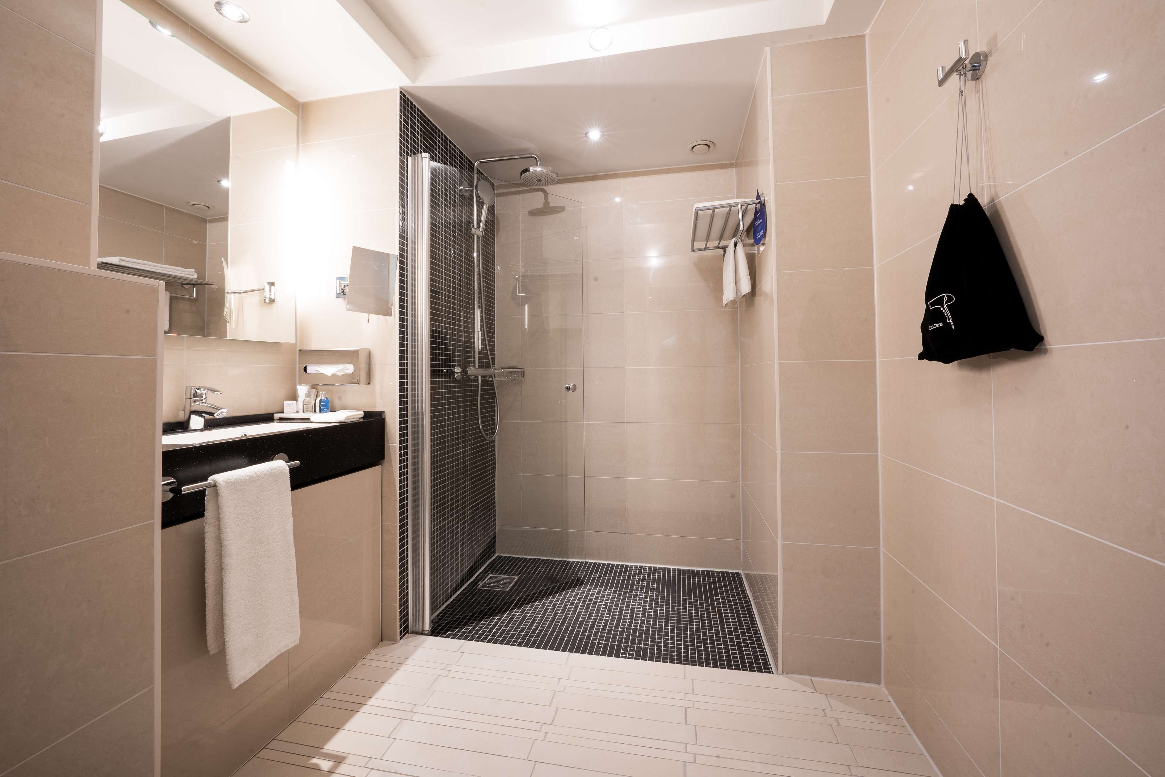Une salle de bain moderne avec une douche, un lavabo et un miroir.