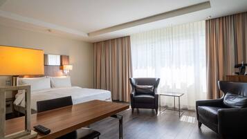 Een hotelkamer met een bed, een bureau, een stoel, een klein tafeltje en een lamp.