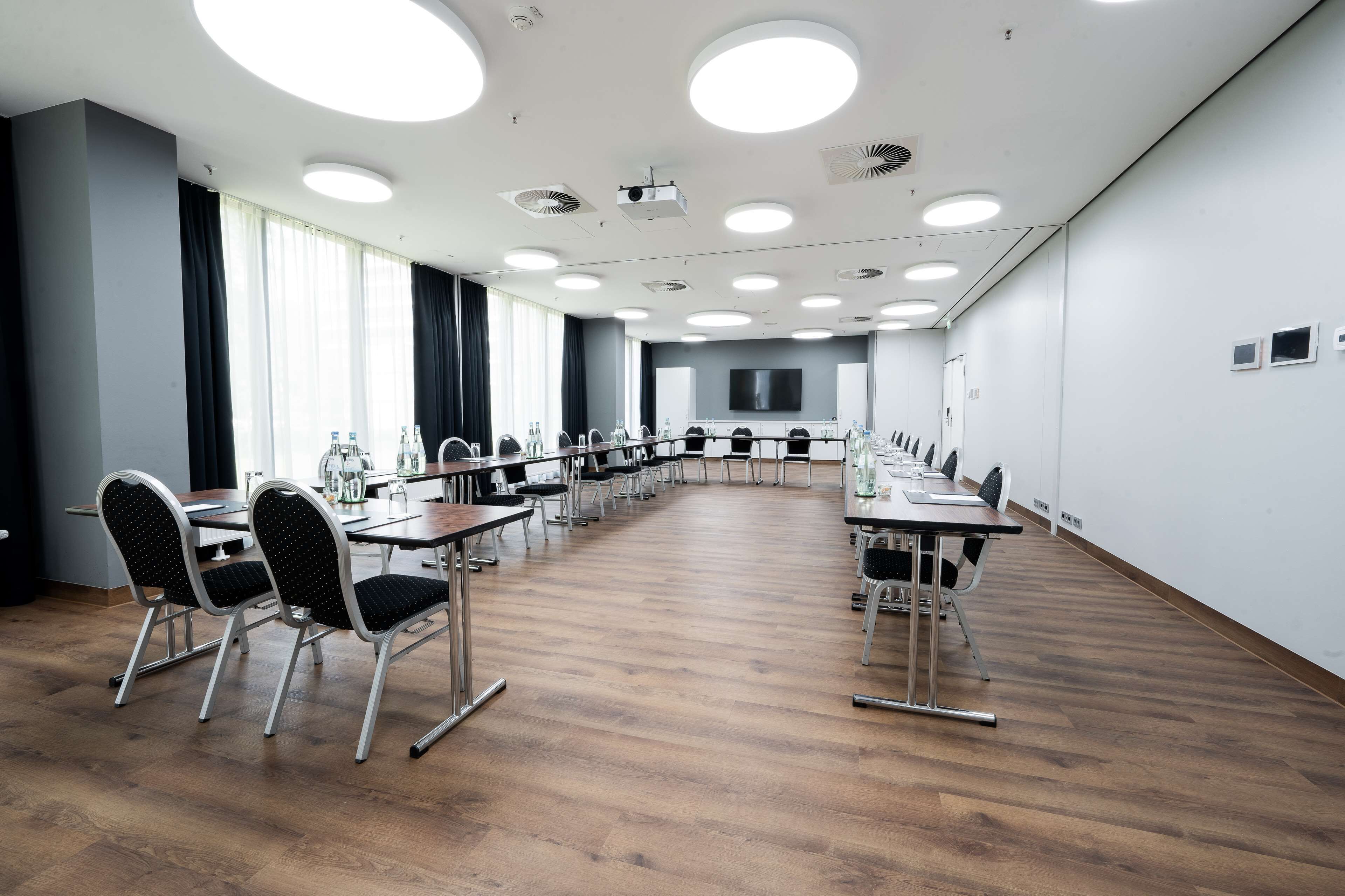 Una sala conferenze con un lungo tavolo, sedie e uno schermo grande.