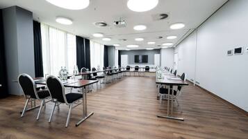 Una sala conferenze con un lungo tavolo, sedie e uno schermo grande.