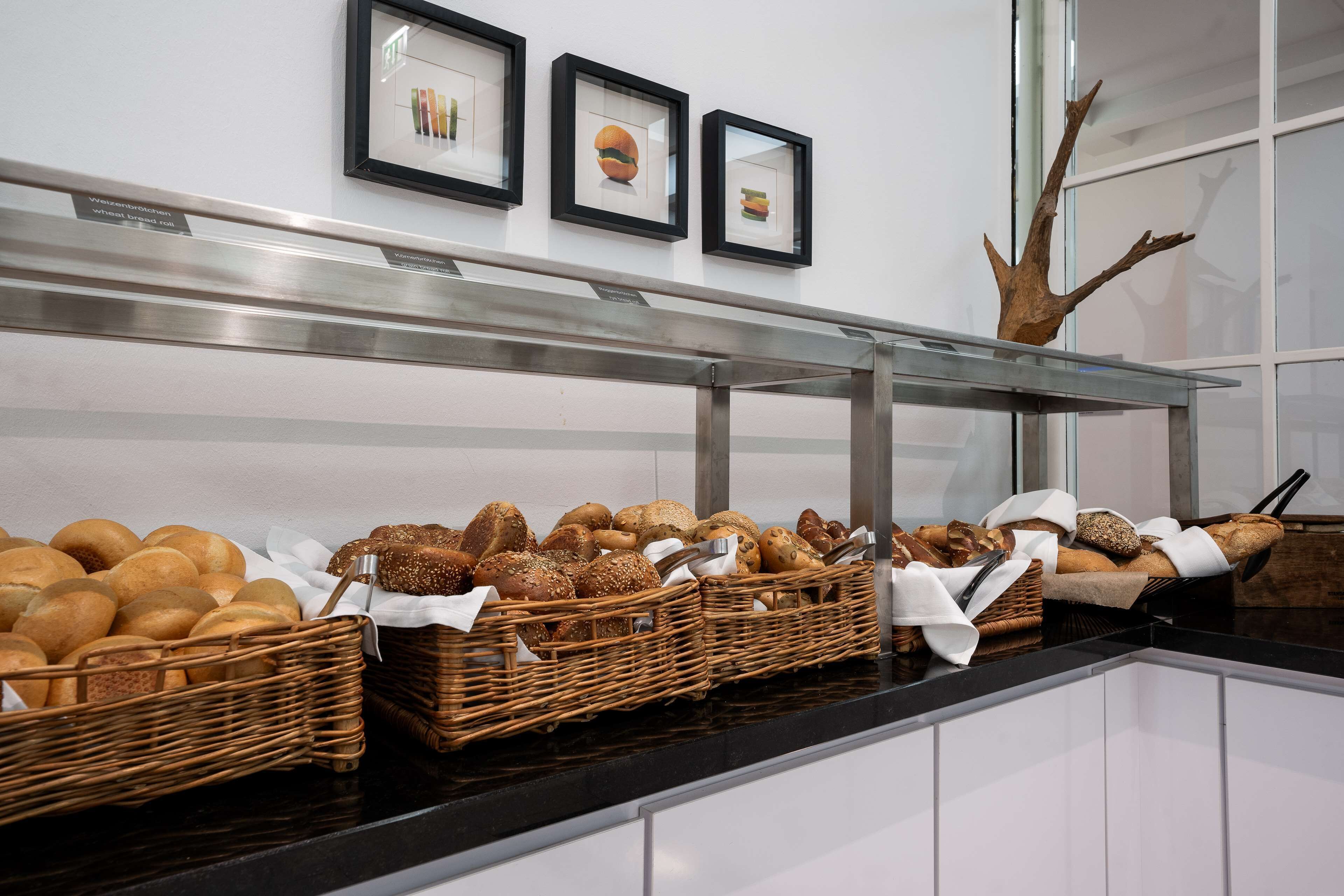 A buffet area with various breads and pastries displayed in wicker baskets on a black countertop.